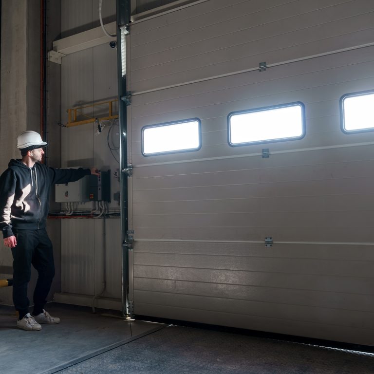 The male engineer is using the ?ontrol units for gates and loading bridges. Control system for warehouse loading bays