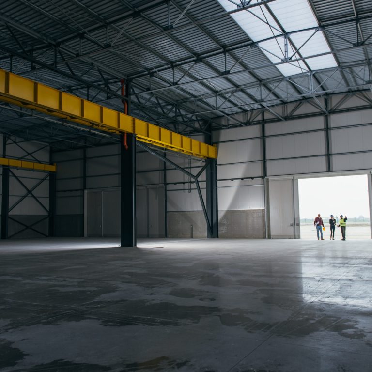 Architect team At Work Site With Blueprints standing at big hangar doors